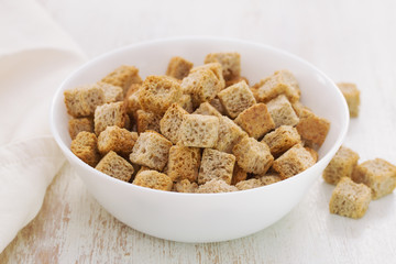 dry bread in white bowl on wooden background