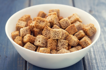 dry bread in white bowl on wooden background