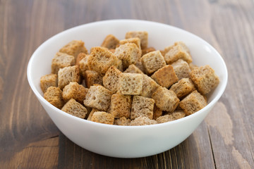 dry bread in white bowl on wooden background