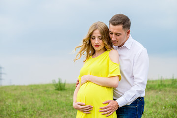 Portrait beautiful young couple waiting for baby. Photo shoot at nature