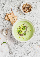Broccoli cream soup with flax seeds and crackers on a light background, top view