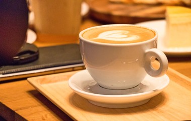 Coffee in white cup with coffee arts on the top on the wooden tray