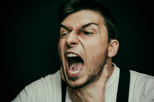 Hombre joven con una mano al cuelo gritando y lleno de golpes y heridas