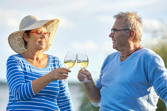 Seniorenpaar trinkt Wein am See, Ausflug genießen