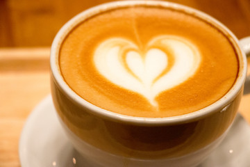 Coffee in white cup with coffee arts on the top on the wooden tray