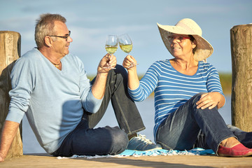 romantisches Picknick am Steg mit Wein, Seniorenpaar