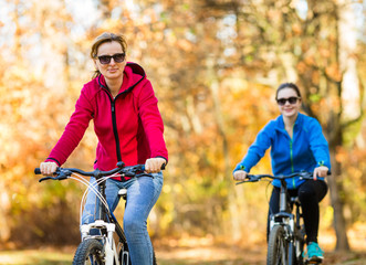 Two women riding bicycles in city