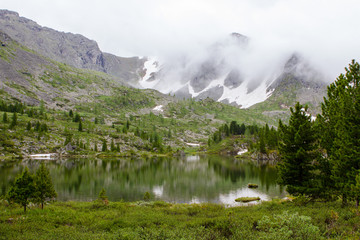Karakol lake and mountain in fog in Altay mountains