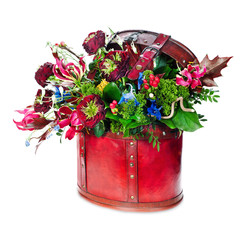 Colorful abstract floral arrangement of roses, lilies, irises and maple leaves in red leather bag isolated on white background.