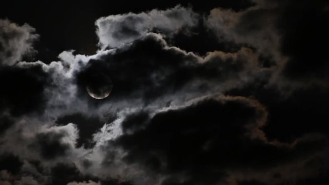 Full moon disappearing in the tatters of dark clouds