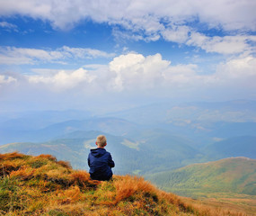 A tourist sits and looks into the distance. Man sit. Wonderful mountain landscape. Autumn is time