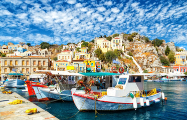 Fototapeta na wymiar Old fishing Boats at Simi , the background of beautiful multi-colored buildings in the island