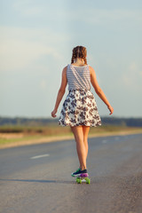 Young cute girl rides skateboard on road