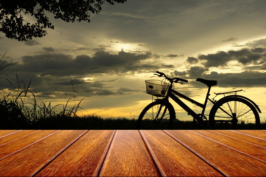 perspective wood table with backgound of bicycle sillouette at sunset nature background