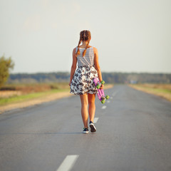 Young cute girl rides skateboard on road