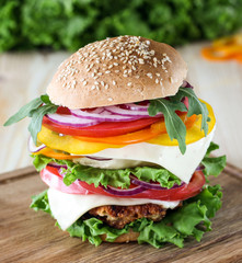 The burger with fresh vegetables on a wooden board