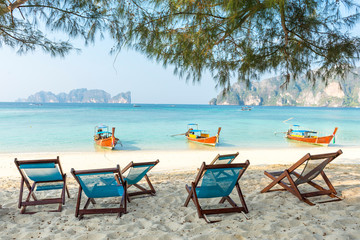 Bamboo beach chairs and traditional long-tail boats on beautiful