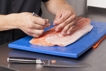 Chef removing the bones of salmon on a cutting board - obrazy, fototapety, plakaty