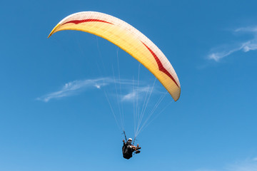 Paraglider flying in blue sky.