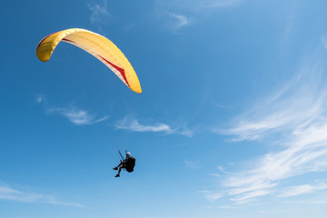 Paraglider flying in blue sky.