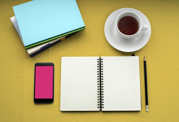 Fototapeta na wymiar Tea in white cup with Journal book and smartphone
