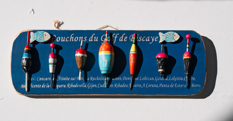 Un pannello di legno blu con una collezione di sugheri e galleggianti per la pesca appeso al muro © Naeblys