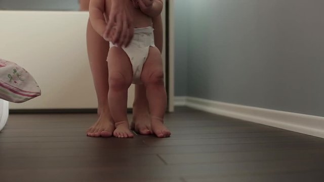 Mom teaches a child to walk on the floor