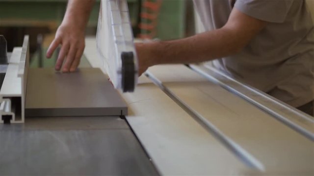 Carpenter is trimming a wood in carpentry shop.