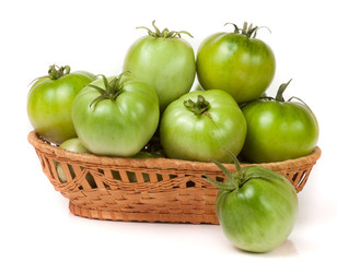 unripe green tomatoes in a wicker basket isolated on white background
