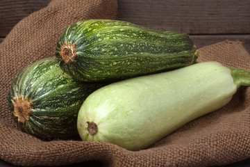 green zucchini and courgette on sackcloth wooden background