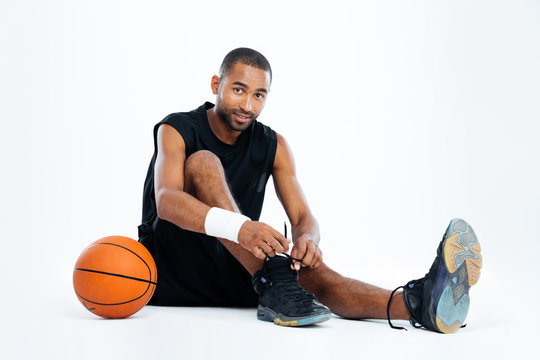Handsome young man basketball player sitting and tying laces