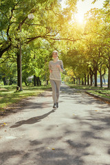 Young girl with blue eyes joging in the park. Autumn weather, yellow foliage.