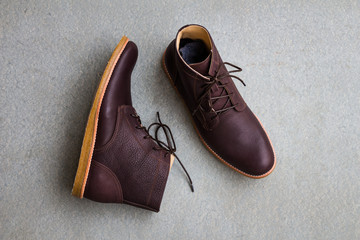 Men's accessories with brown leather boots on gray grunge background