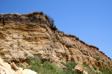 Fototapeta na wymiar Sandy cliff above the sea and the sky.