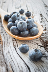 Blueberries in wooden ladle on wooden table background, rustic style 