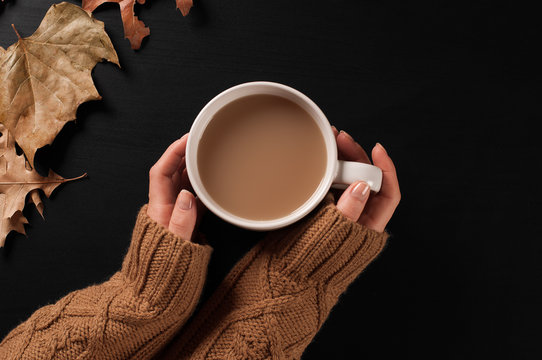 Autumn mood, woman holding coffee in hands on wooden background