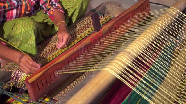 Closeup old woman hands weaving mats from dry reed.