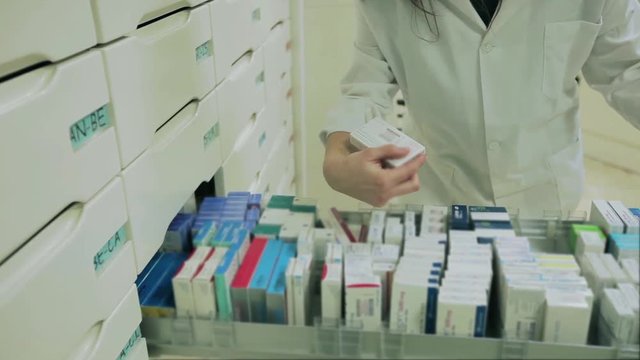 Good looking Pharmacist woman taking medicine from a drawer