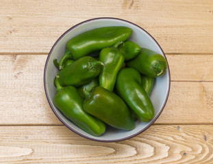 Green bell pepper in a bowl on a wooden table.
