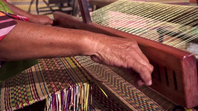 Closeup old woman hands weaving mats from dry reed.