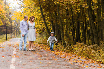 Fototapeta premium Happy young family walking down the road outside in green nature.