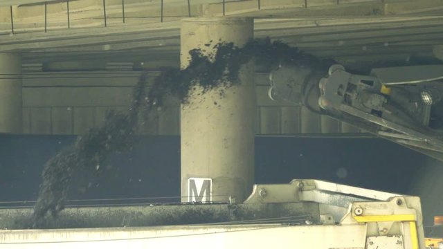 Cold milling machine removes the roadbed under the bridge, crushed asphalt is moving on conveyor, slow motion 