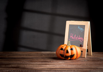 Halloween pumpkin head jack lantern and a chalkboard on wooden