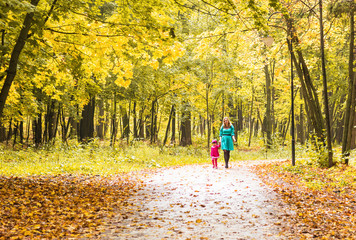 Fototapeta premium Young mother walk with her daughter in autumn park