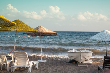 Fototapeta na wymiar Boat on the beach, umbrellas, beach chairs on the ocean.