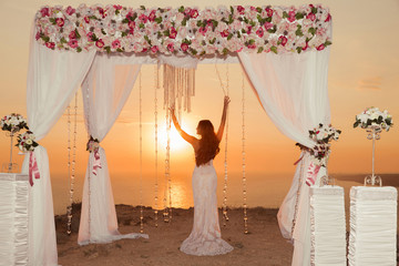 Sunset. bride silhouette. Wedding ceremony arch with flower arra