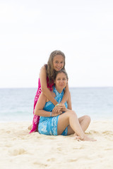 Fototapeta premium Lovely Mother and Girl Sitting on the Beach