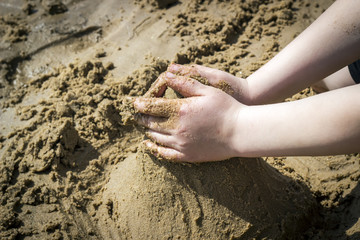 Child's hand build stronghold in salt white sand and.