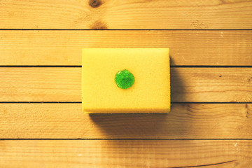 Yellow dish sponge with a drop of dishwashing detergent