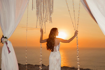 Sunset. bride silhouette. Wedding ceremony arch with white curta